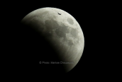 An airplane passes in front of the moon